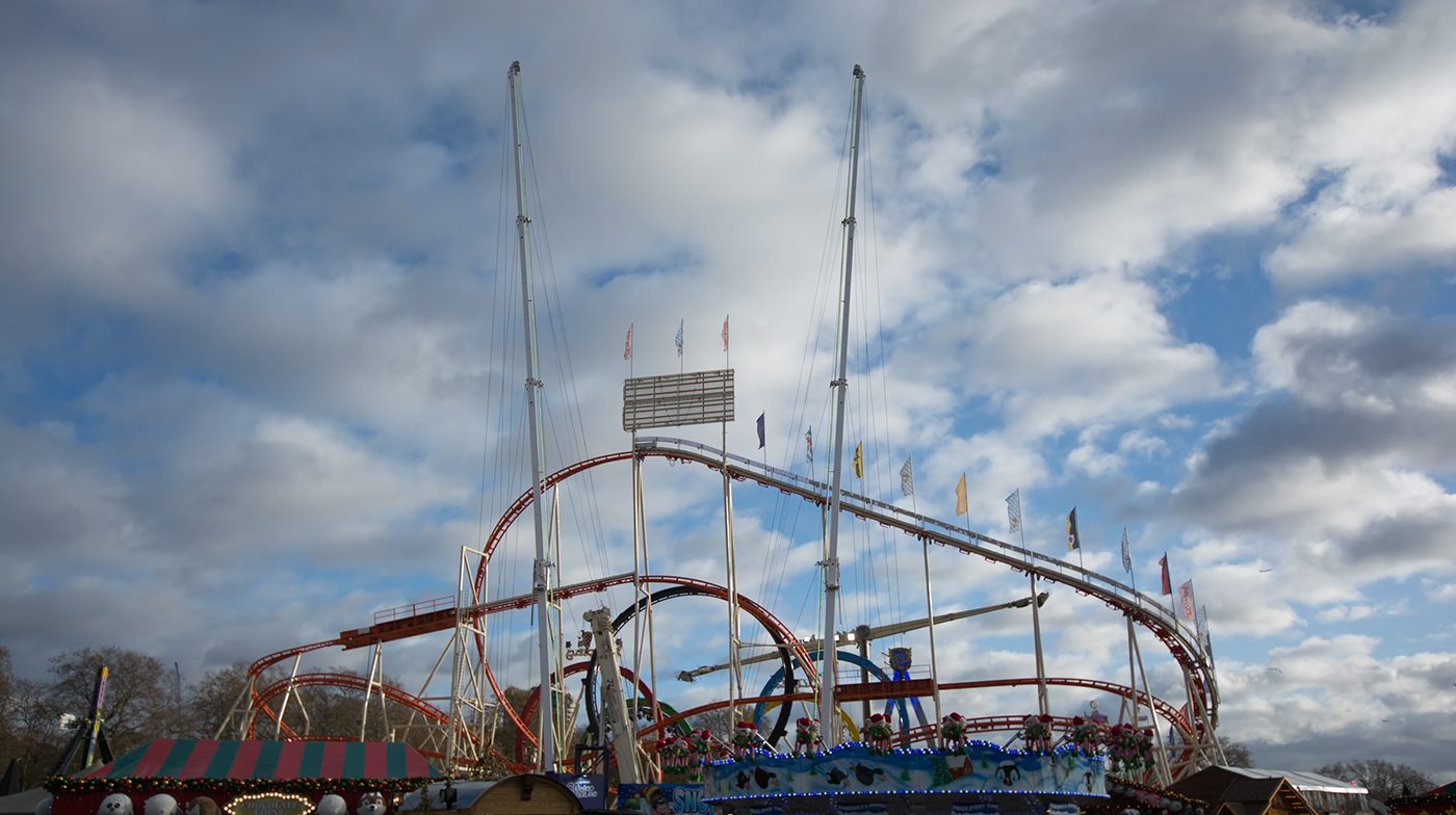 Red roller coaster over a festive market stall under clouds, before the preset