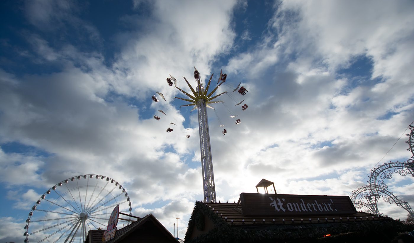Swing ride and Ferris wheel against a bright cloudy winter sky, before the preset